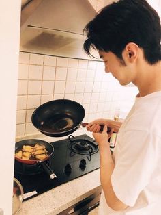 a young man cooking food on top of a stove next to a frying pan