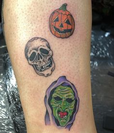 a person with a tattoo on their leg that has two skulls and three pumpkins