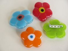 four different colored flower shaped buttons on a white surface, with one button facing the camera