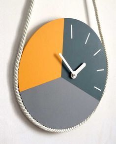 a clock that is on the wall with ropes attached to it's sides and two different colors