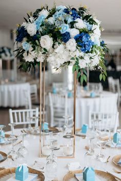 a centerpiece with blue and white flowers is on top of a table at a wedding reception