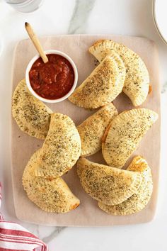 baked pastries on a cutting board with dipping sauce