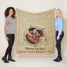 two women standing next to each other holding up a blanket with an image on it