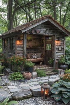 a small wooden shed in the middle of a forest with flowers and plants around it