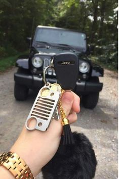 a person holding a car key chain with a jeep in the background