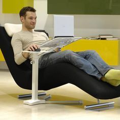 a man sitting in a chair with his feet up on the table while using a laptop