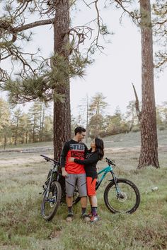 a man and woman standing next to each other in the woods