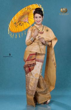 a woman is dressed in traditional thai garb and holding an orange parasol while standing against a blue background