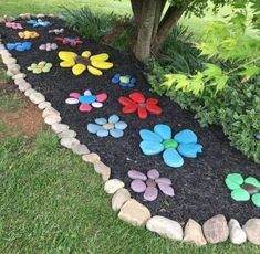 a garden filled with lots of different colored rocks and flowers on top of black mulch