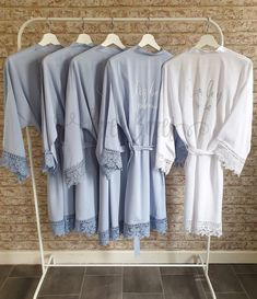 four robes are hanging on a rack in front of a brick wall and tile floor