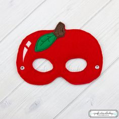 a red mask with a green leaf on it sitting on top of a white table