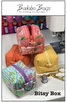 three bags sitting next to each other on top of a table with scissors and thread