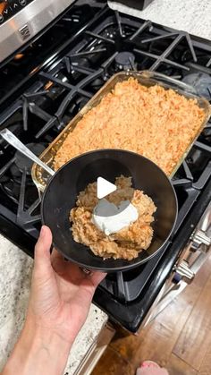 a person holding a pan with food on it in front of an oven and stove top