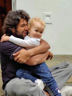 a man sitting on the ground holding a small child