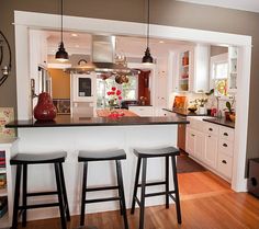 a kitchen with three stools in front of an island