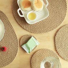 the table is set with plates, cups, and saucers on jute placemats