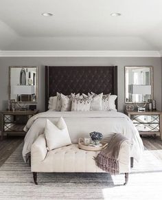 a bedroom with a large bed and two mirrors on the wall