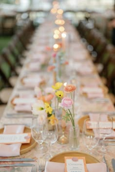 a long table with place settings and flowers