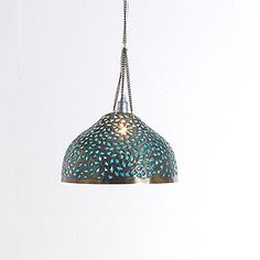 a blue lamp hanging from a chain on a white wall in a room with no one around it