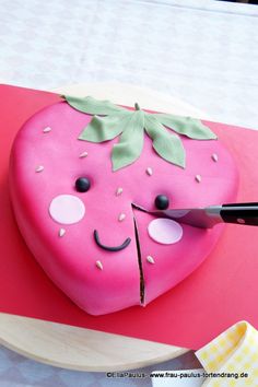 a cake shaped like a strawberry with a knife sticking out of it's side