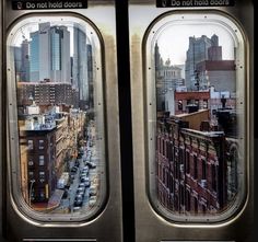 the view from inside an airplane window looking down on a cityscape with tall buildings