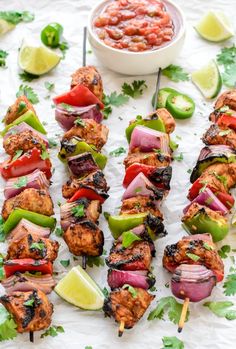 chicken kabobs on skewers with salsa and limes