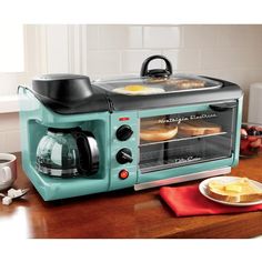 a blue toaster oven sitting on top of a wooden table next to a plate of food