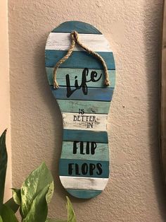 a wooden sign that says life is better in flip flops hanging on the wall