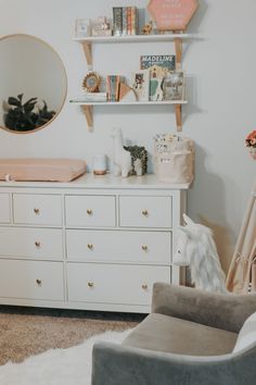 a baby's room with a dresser, mirror and toys on the shelves in it