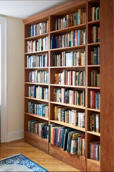 a bookshelf filled with lots of books on top of a hard wood floor