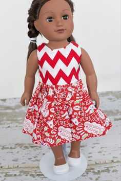 an american girl doll wearing a red and white chevroned dress with her hair in pigtails