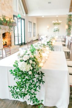 a long table with white flowers and greenery is set up for a formal function