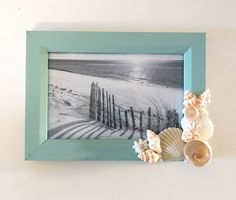 seashells and sea glass are placed in front of a blue frame on the wall