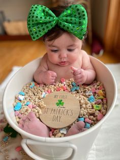 a baby in a white bowl with a green bow on her head