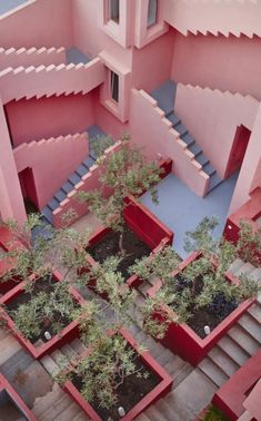 an aerial view of a pink building with trees in the courtyard