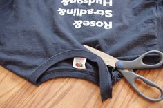 a pair of scissors sitting on top of a black t - shirt with words written in white