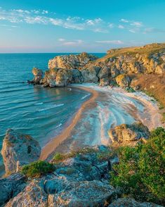 the beach is surrounded by large rocks and water