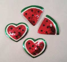 four pieces of sequinized watermelon shaped broochies on a white surface