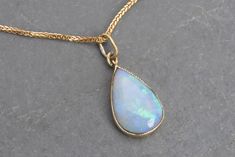 18k gold pendant featuring a drop-shaped milky crystal opal, encased in an 18k gold frame with a delicate milgrain border.  The opal has a sky blue hue with captivating green and blue play-of-color, its chain's marked "750" for gold purity, while the pendant itself, though unmarked, has been tested and confirmed as 18k gold.  Very good general condition. Pendant measures 19 mm x 9 mm, chain lenght 45 cm, total weight 2.82 grams. Let me know if you would like further photos or information, layaway options are available for all purchases over $300. Thanks for your visit! Elegant Drop Opal Jewelry, Elegant Ethiopian Opal Cabochon Necklaces, Elegant Pear-shaped Opal Jewelry, 18k Gold Chain, Crystal Opal, A Sky, Opal Crystal, Green And Blue, Blue Hues