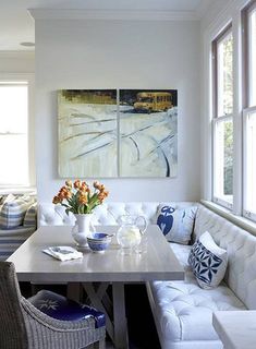 a living room filled with furniture and a white table in front of two large windows