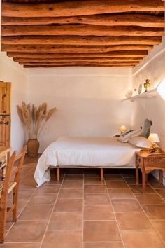 a bed sitting under a wooden ceiling next to a table and chair in a room