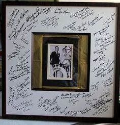 an autographed photo is in a frame with writing on the wall behind it