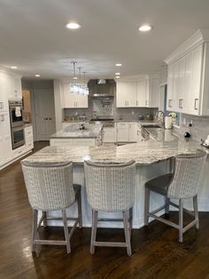 an image of a kitchen with white cabinets and marble counter tops in the center island