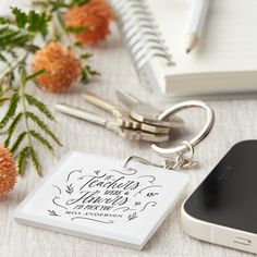 there is a keychain that has a phone on it next to some flowers