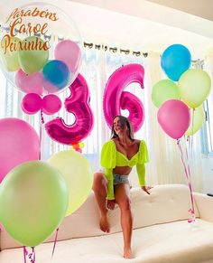 a woman sitting on top of a couch surrounded by balloons