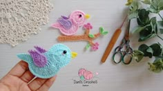 crocheted birds sitting on top of a table next to scissors