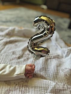 a baby is holding some foil balloons in the shape of a number 2 on top of a bed