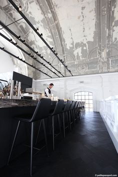 an instagram photo of a restaurant with black chairs and white walls, the ceiling is covered in peeling paint