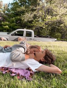 two people laying in the grass near a truck