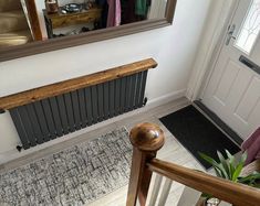 a hallway with a radiator, rug and mirror